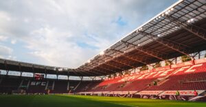 Wide-angle shot of Geneva's SFC stadium with empty seats and sky highlights. World Cup logistics statistics