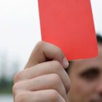 Close-up of a referee holding a red card, signaling a penalty in a soccer match. World Cup red cards