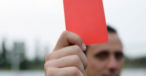 Close-up of a referee holding a red card, signaling a penalty in a soccer match. World Cup red cards